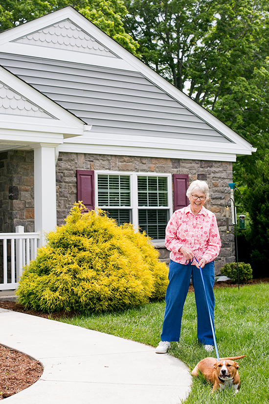 Female resident with dog on leash in front of cottage
