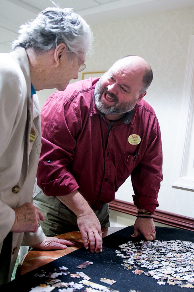 Memory care resident working on a jigsaw puzzle with a staff member