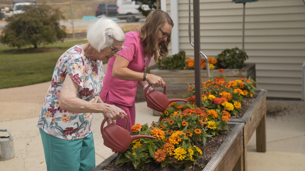 Woman CNA with woman resident gardening